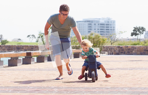 Image of Happy, running and motorbike with child and father playing in park for bonding, laugh and helping. Smile, happiness and energy with man and young boy riding on scooter for playful, learning or summer