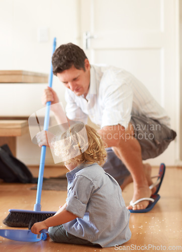 Image of Man is sweeping with boy kid, cleaning with broom and help with mess on floor while at home together. Hygiene, chores and house work with man and child bonding and helping with crumbs on ground