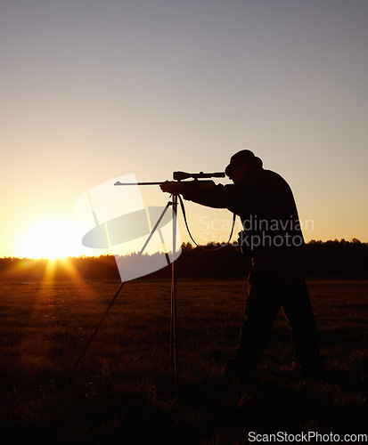 Image of Hunting at sunset, man with rifle stand in nature to hunt game for sport on safari adventure. Sky, silhouette and hunter with gun, focus on target and evening setting sun for shooting hobby in bush.