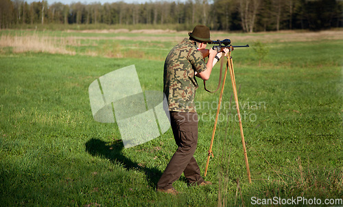 Image of Hunter, gun and man in field in nature on a Africa safari for animal shooting with a weapon on vacation. Hunting sport, male person and target hunt practice of a traveler in camouflage with a scope