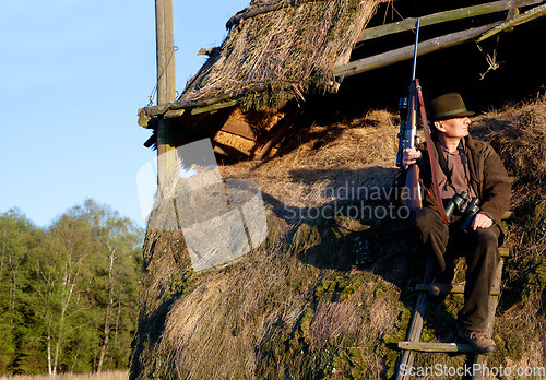 Image of Hunter, game shooting and man on a safari gun at outlook post for animal and wild hunting. Male person, poacher and hunter waiting for wildlife sports outdoor for scope watching at sunrise as a hobby