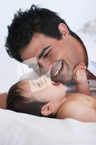 Image of Baby, laugh and dad on a bedroom bed with happiness, bonding and parent care with smile. Father, happy and young child together in a home playing and kid laughing from papa love and youth support