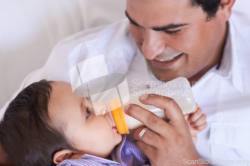 Image of Baby, feeding and dad with child at home with a bottle of milk with happiness with kids. Family, young child and drink for growth and development with a father feeling proud and happy in a house