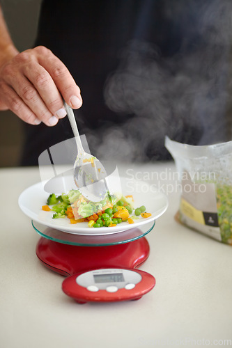 Image of Scale, food and man with vegetables in kitchen to measure portion for calories, nutrition and balance diet. Cooking, hungry and hands of male person weigh healthy meal for lunch, dinner and supper