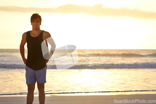 Image of Portrait, mockup and a man on the beach at sunset standing on sand by the sea at the coast outdoor. Nature, water and travel with a handsome young male tourist at the ocean during holiday or vacation