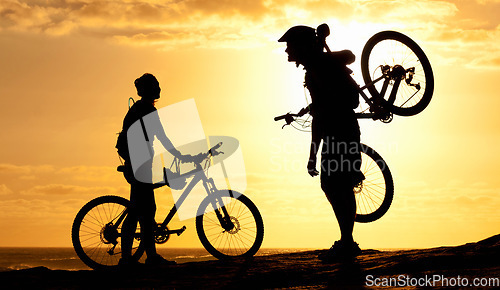 Image of Sunset, silhouette and couple with bike at beach for relax, fitness and summer break. Travel, vacation and training with man and woman with bicycle on coastline for cycling, bonding and wellness