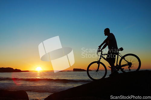 Image of Man, beach and silhouette with mountain bike, sunset and mockup space by waves for summer cycling adventure. Cyclist, freedom and fitness with bicycle, training or journey by ocean in dusk sunshine