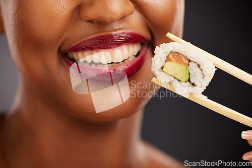 Image of Mouth, eating and woman with sushi and chopsticks in studio for healthy food or teeth. Black female model with makeup on dark background for wellness glow, diet and seafood or salmon closeup