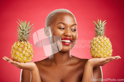 Image of Pineapple, beauty and face of a woman in studio for healthy food, diet or fruit. Black female model with makeup on red background for wellness glow, natural cosmetics and tropical or citrus skin care