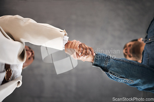 Image of Business people, handshake and meeting in partnership, teamwork or trust for unity below at office. Low angle of employees shaking hands for introduction or greeting in agreement or deal at workplace