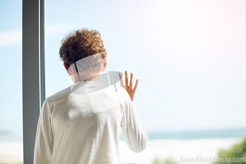 Image of Sad, depression and hope of a child at window while bored lonely and thinking. Depressed, psychology and autism boy child with anxiety problem in isolation with hand by mockup space in house