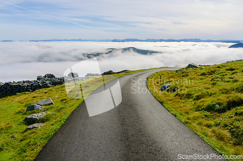 Image of Mountain peaks poked out of fog on the coast by a road