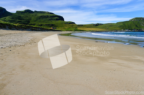 Image of Beach by the coast with green grass up the hill