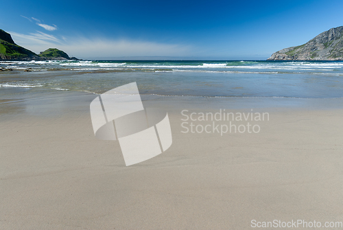 Image of beach sand and waves against a blue sky