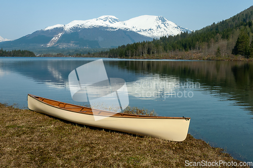 Image of Canoe lying by the water and mountains reflected in the water