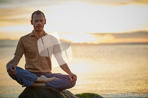 Image of Go deep and then let it go. Shot of a man sitting in the lotus position during his yoga routine at the beach.