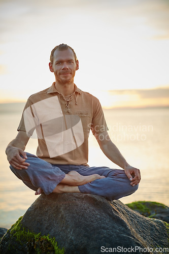 Image of Happiness is right here, right now. Shot of a man sitting in the lotus position during his yoga routine at the beach.