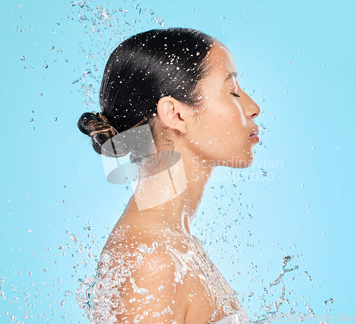 Image of Skincare, water and profile of woman on blue background for wellness, healthy skin and cleaning in studio. Beauty, shower and female person with splash for facial grooming, washing and body care