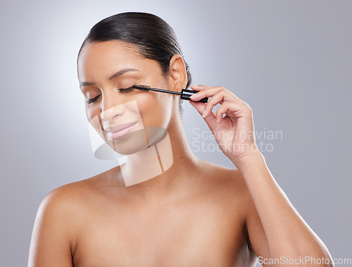 Image of Brush, mascara and woman in studio for makeup, cosmetics and results on grey background. Eyelash, curling and face of Indian female model with beauty tool for treatment, application or volume
