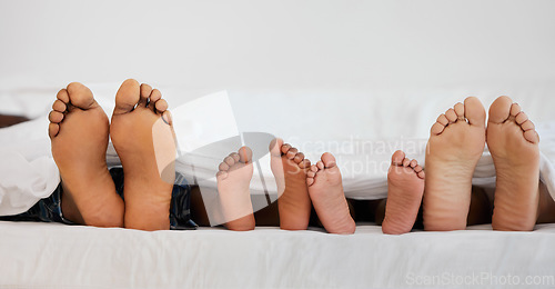 Image of Love, bed and closeup of family feet relaxing, laying and bonding in the bedroom with a blanket. Zoom of a mother, father and children resting or sleeping barefoot together on weekend in their house.