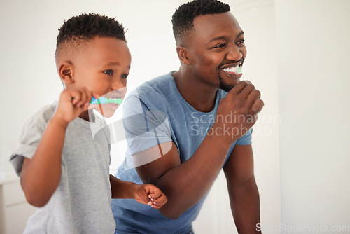 Image of Father brushing his teeth with his child for oral hygiene, health and wellness in the bathroom. Dental, teaching and young African man doing his morning mouth routine with his boy kid at their home.