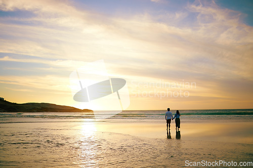 Image of Couple, sunset and walk by ocean with space for mockup in summer sunshine with love, care and bond on holiday, Man, woman and holding hands with sky background, beach and clouds on romantic vacation