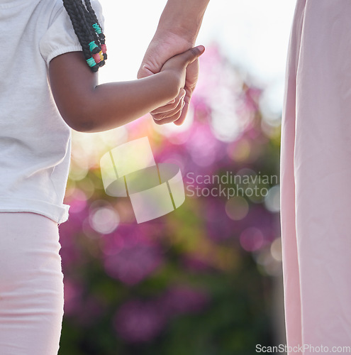 Image of Mother, child and holding hands for a walk outdoor in nature or garden with trust, security and safety. Woman and girl kid or daughter together at a park for family time, support or love and care