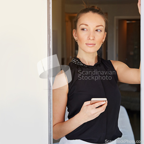 Image of Waiting for an important text. Shot of a young woman using her cellphone in her hotel room.