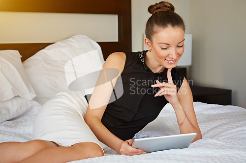 Image of Spending some time online. Shot of a young woman using a digital tablet in her room.