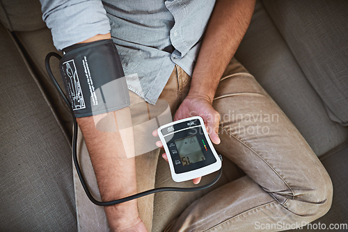 Image of Hypertension, closeup and person with home test for blood pressure on living room sofa for medical or health exam. Monitor, reading and man with equipment for chronic disease or stress from top view