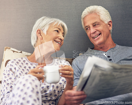 Image of Coffee, newspaper and a mature couple in bed, enjoying retirement in their home in the morning. Tea, reading or love with a happy senior man and woman in the bedroom together to relax while bonding