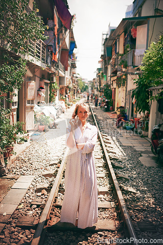 Image of Every town I visit becomes part of me. Shot of a young woman walking on train tracks through the streets of Vietnam.