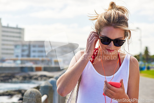 Image of Travel, woman with smartphone and earphones in city street listening to music. Traveling, technology and female person online streaming podcast or radio outside in urban a road with cellphone