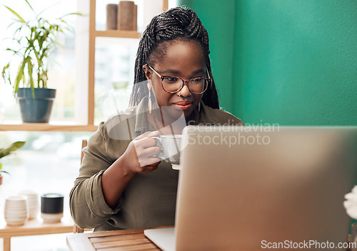 Image of Coffee is the ultimate bloggers fuel. Shot of a young woman having coffee and using a laptop at a cafe.