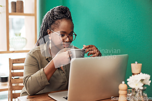 Image of Coffee blogging is kinda her thing. Shot of a young woman having coffee and using a laptop at a cafe.