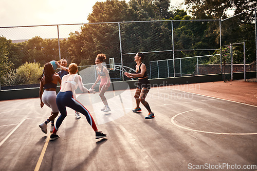 Image of Trying to get through. Cropped shot of a diverse group of sportswomen playing a competitive game of basketball together during the day.