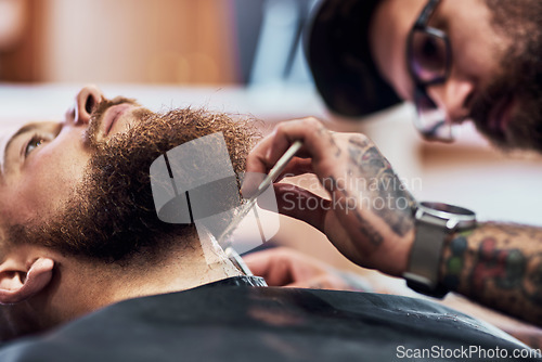 Image of Dont come between a man and his beard. Cropped shot of a handsome young man getting his beard trimmed and lined up at a barbershop.