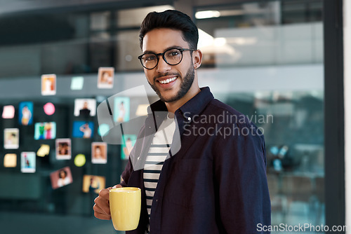 Image of Caffeine helps me get through the day. Cropped portrait of a handsome young businessman wearing spectacles and standing in his office while drinking a cup of coffee.