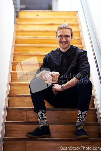 Image of I need coffee to recharge. Full length portrait of a handsome young businessman sitting on the office staircase and holding a cup of coffee.