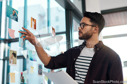 Image of This is the one I need. Cropped shot of a handsome young businessman standing alone in his office and working with post-its and polaroids.