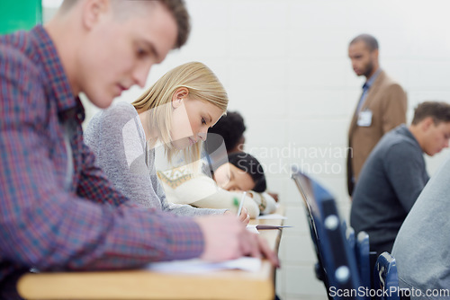 Image of This lecture hall is completely focused. Shot of a group of university students writing an exam.