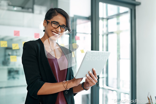 Image of Its been a busy but successful day. Shot of an attractive young businesswoman standing alone in the office and using a digital tablet.