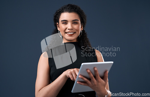 Image of Staying up to date with social media. Cropped portrait of an attractive young businesswoman standing alone and using a tablet against a gray background in the studio.