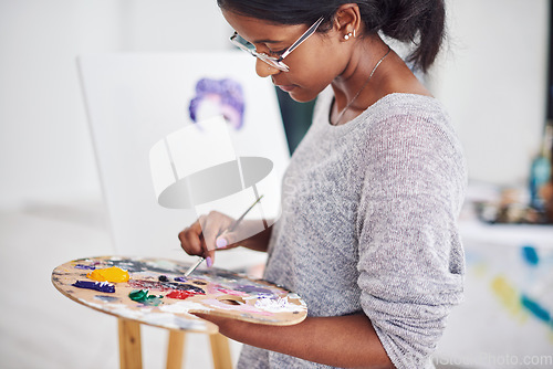 Image of Something beautiful is about to come to life. Cropped shot of a beautiful young woman painting in a art studio.