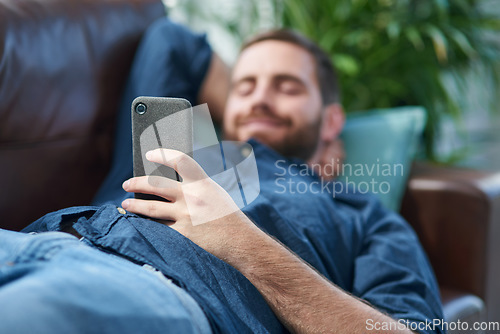 Image of Nothing says self service like smart apps. Shot of a young man using a smartphone while relaxing on a sofa.