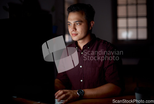 Image of Wrapping up some deadlines. Shot of a young businessman working on a computer in an office at night.
