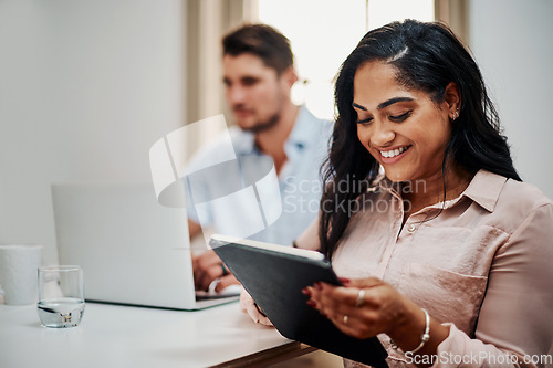 Image of Facilitating a meeting with awesome functionality. Shot of a young businesswoman using a digital tablet during a meeting in a modern office.