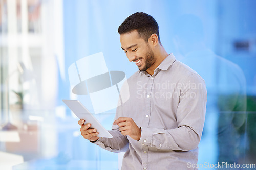 Image of Technology, man on a tablet and standing with smile in a office at his workplace. Social networking or connectivity, online communication, happiness and male person reading a email or report.