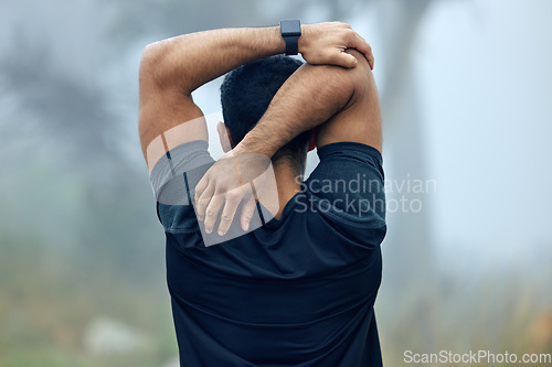 Image of Fitness, back and man stretching arms for exercise, workout or training in the nature outdoors. Rear view of fit and active male person or runner in warm up stretch for running or cardio exercising