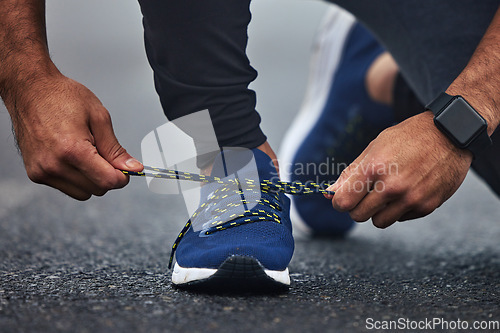 Image of Man, hands and tie shoes on road for running, fitness or cardio workout on asphalt in the outdoors. Hand of male person, runner or athlete tying shoe and getting ready for sports training on street